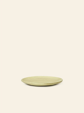The ferm LIVING Flow Plate, Small, features a simple round shape in beige porcelain with a slightly raised rim, displayed centered against a plain, light background.