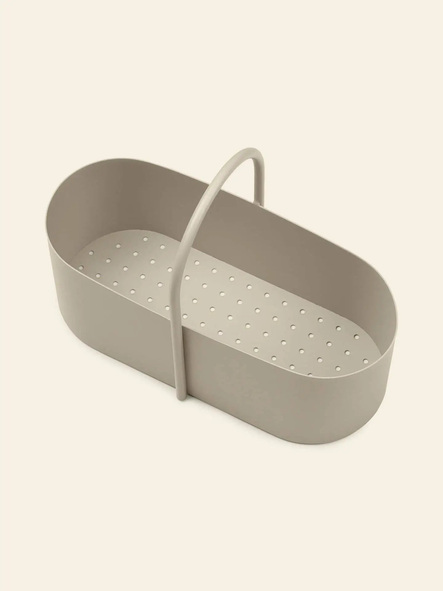 The ferm LIVING Grib Toolbox by ferm LIVING, featuring an oval shape, beige color, plastic build, slim design with small bottom holes and a curved top handle, is shown on a plain light background.