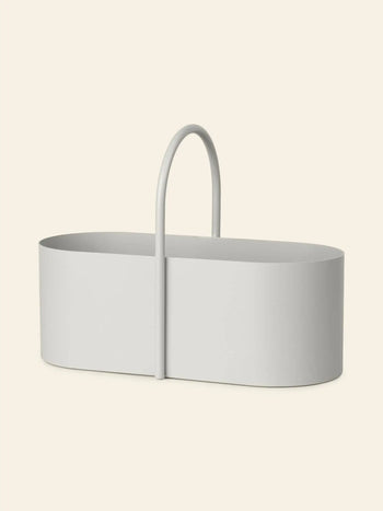 The ferm LIVING Grib Toolbox by ferm LIVING is a minimalist, oval-shaped white organizer with a slim design, smooth sides, and a central upright handle—ideal for stationery—set against a solid light beige background.