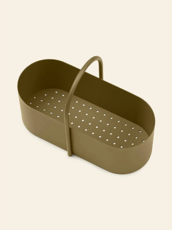 The ferm LIVING Grib Toolbox by ferm LIVING is an olive green, oval-shaped organizer with a slim handle and perforations at the base, displayed on a plain light beige background.