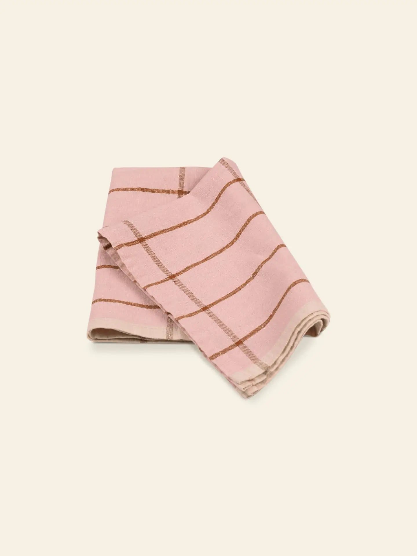 The ferm LIVING Hale Tea Towel by ferm LIVING is a folded pink towel with a brown plaid pattern, displayed on a plain light background.