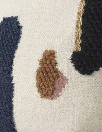 Close-up of the ferm LIVING Loop Cushion, crafted from New Zealand wool with tufted embroidery in navy, brown, pink, and black on a cream backdrop—highlighting abstract shapes and contemporary stitched details by ferm LIVING.
