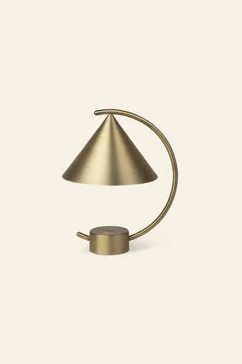 The ferm LIVING Meridian Lamp by ferm LIVING features a sculptural brass design with a conical shade and curved arm, set against a light beige background. Its minimalist, contemporary lines lend an elegant, modern touch.