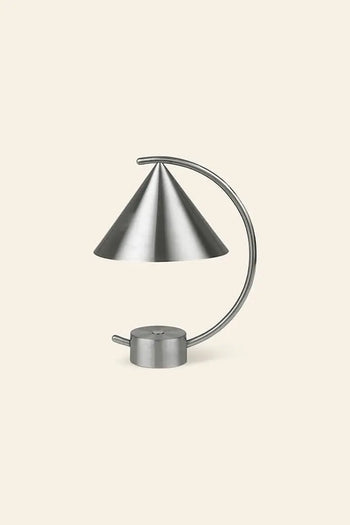 The ferm LIVING Meridian Lamp by ferm LIVING is a modern, minimalist desk lamp with a conical shade and curved arm, crafted from powder coated steel and set against a light beige background.