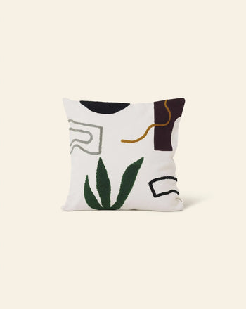 The ferm LIVING Mirage Cushion by ferm LIVING features embroidered green leaf-like shapes and curved lines in black, gray, gold, and burgundy on a white background, creating an abstract nature-inspired design.
