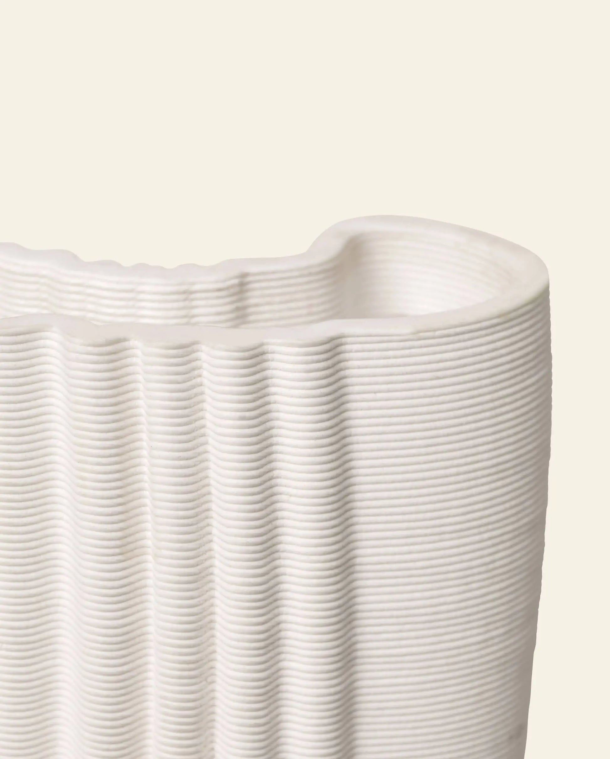 Close-up of the ferm LIVING Moire Vase by ferm LIVING, showcasing its ribbed ceramic surface and wavy rim against a light beige background. The vase’s elegant, horizontal layered lines emphasize its refined texture.