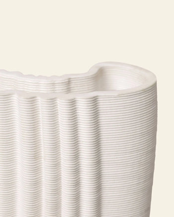 Close-up of the ferm LIVING Moire Vase by ferm LIVING, showcasing its ribbed ceramic surface and wavy rim against a light beige background. The vase’s elegant, horizontal layered lines emphasize its refined texture.
