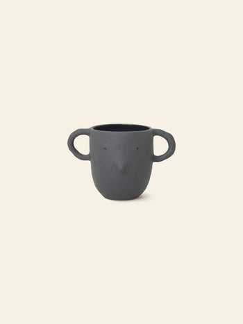 The ferm LIVING Mus Plant Pot, Large features a black ceramic finish with mouse handles and a subtle face design—two eyes and a petite nose—set against beige. Playful and charming, it doubles as both décor and plant pot.