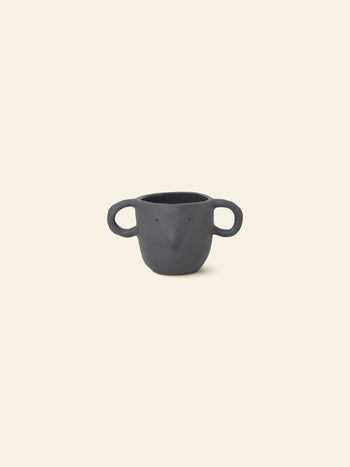 The ferm LIVING Mus Plant Pot, Small—black ceramic with mouse-ear handles and beak detail—features a whimsical animal-inspired design, perfect as a quirky plant pot and showcasing signature ferm LIVING style against a beige backdrop.