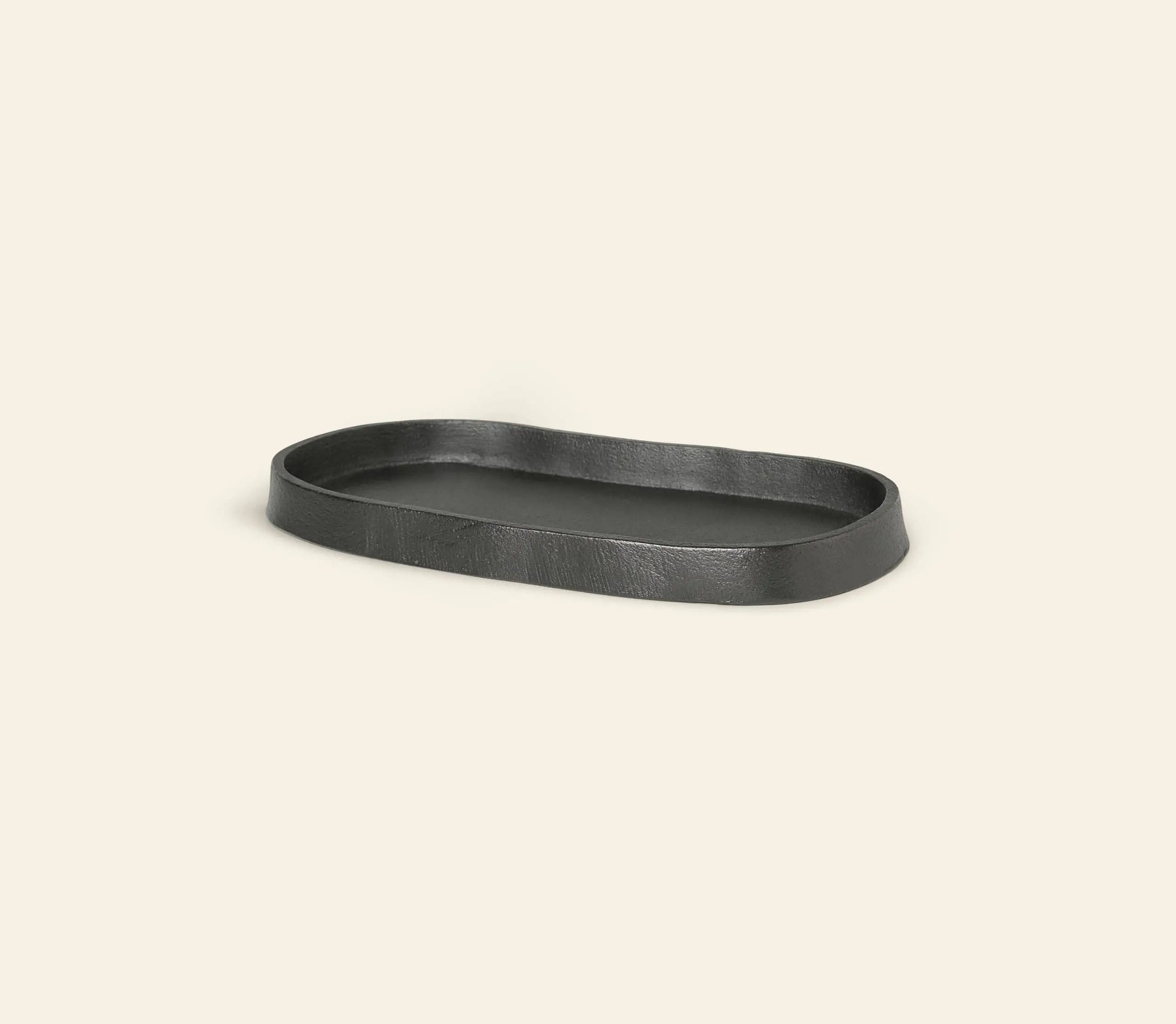 The ferm LIVING Yama Tray, Oval, by ferm LIVING, is a black tray with slightly wavy edges and a minimalist design, shown against a light beige background.