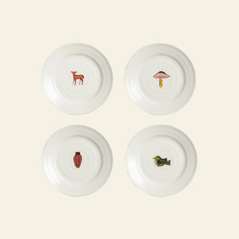The &klevering Autumn Plate Small, Set of 4 by &klevering features white ceramic plates with nature-inspired prints—a deer, mushroom, owl, and bird—centered on an autumn-themed backdrop. Perfect for charming table settings.