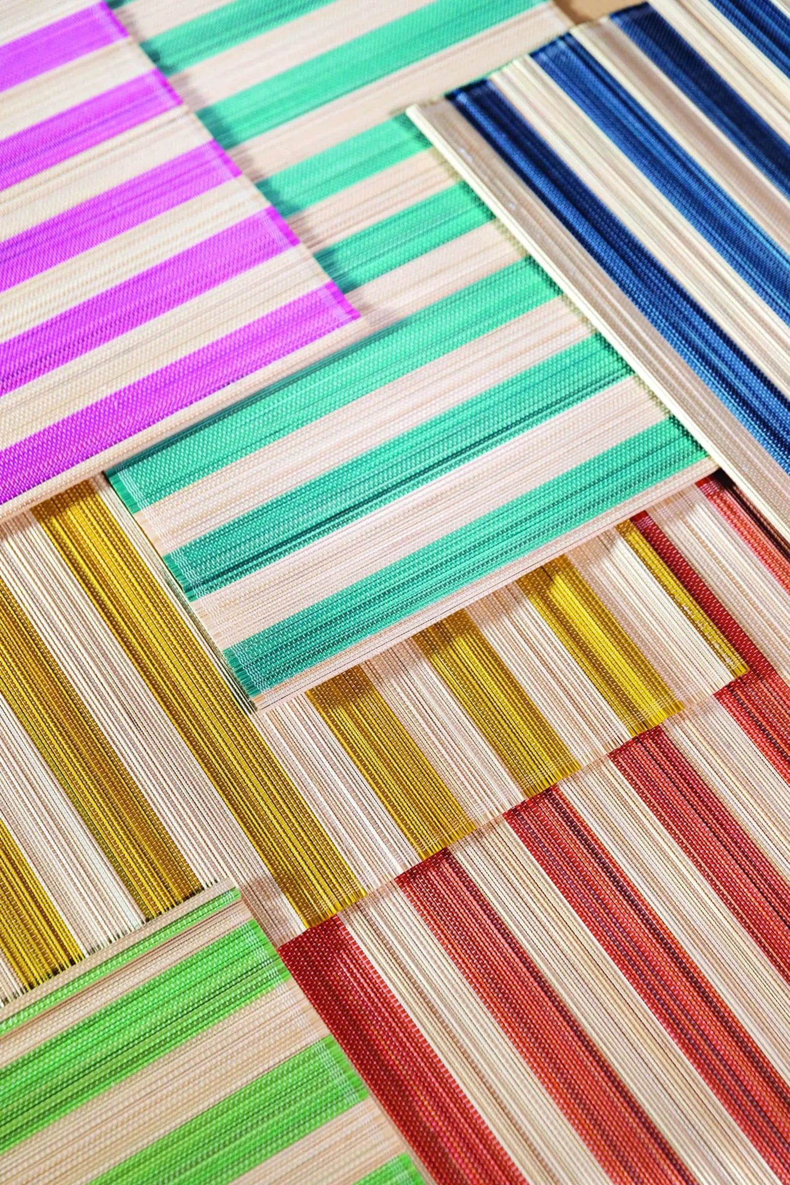 A geometric close-up of &klevering Bay Placemats, Set of 6, overlapping in vibrant summer hues with cream and colored stripes—green, blue, pink, yellow, orange, and red—arranged in a layered pattern.