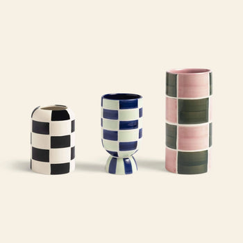 The &klevering Carré Vase, Set of 3 by &klevering features bold checkered designs—one black and white, one blue and white with a rounded base, and one tall with pink and green squares—striking decorative pieces.