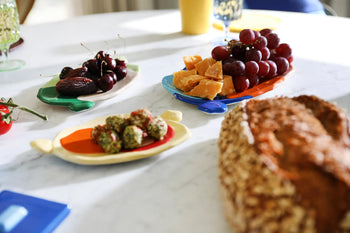 The &klevering Chunky Platter, Large by &klevering showcases bold colors: cheese cubes with grapes, whole dates with cherries, herb-coated snacks, and crusty bread—all artfully arranged for a vibrant display.