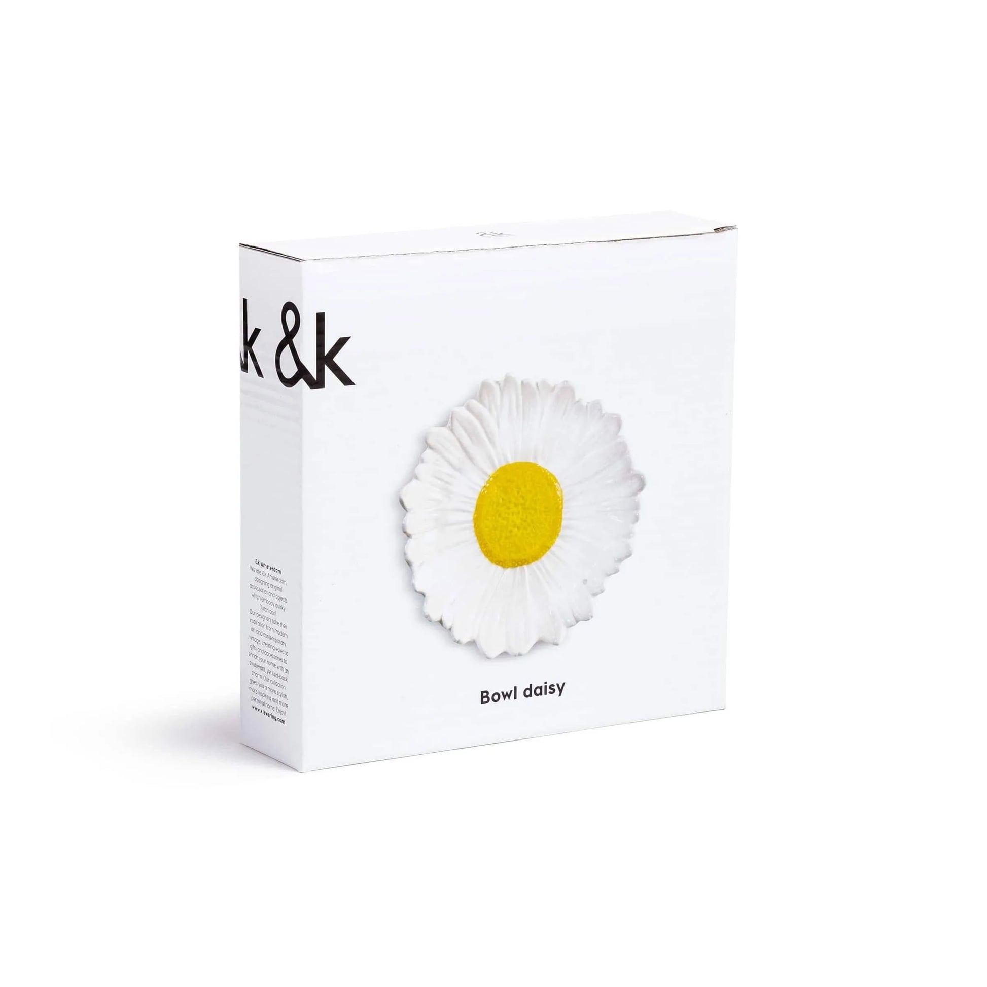 A plain white box with minimal black text displays the &klevering Daisy Bowl—featuring a daisy-shaped design with white petals and a yellow center. Perfect for summer picnics or garden dinners.
