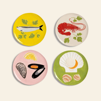 The &klevering De La Mer Plate, Set of 4 features ceramic plates, each hand-painted with a unique seafood design—fish, lobster, mussels with lemon, and scallop—accented with herbs for an artful, ocean-inspired touch.