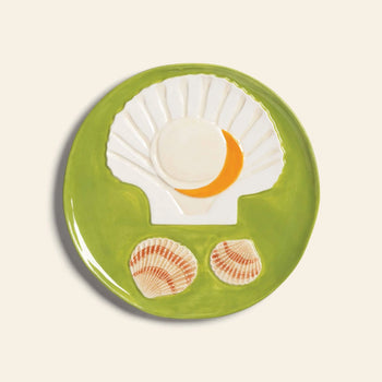 The &klevering De La Mer Plate, Set of 4 features round green hand-painted plates with ceramic scallop shells, orange accents, and brown-striped details, capturing true oceanic charm from the &klevering collection.