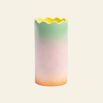 The &klevering Fade Vase, Large by &klevering is a tall ceramic vase with a wavy scalloped rim and pastel gradients—yellow at the top blending into green, pink, and orange—ideal for adding charm to any table. Shown on a plain beige background.