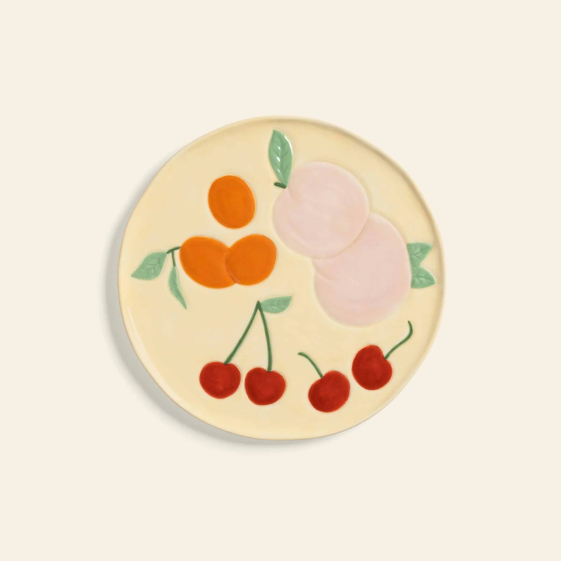 The &klevering Fruitful Plate, Set of 4 by &klevering is a round ceramic plate with vintage charm, featuring hand-painted fruit motifs—cherries, apricots, and peaches—on a cream background.