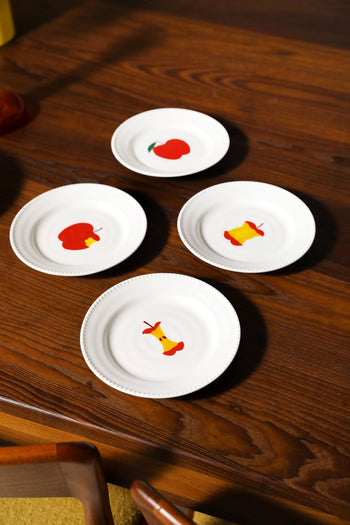 The &klevering Haines Plate Small, Set of 4 features a playful apple design with whole and cored red and yellow apples on white plates, perfect for adding charm to your dining table.