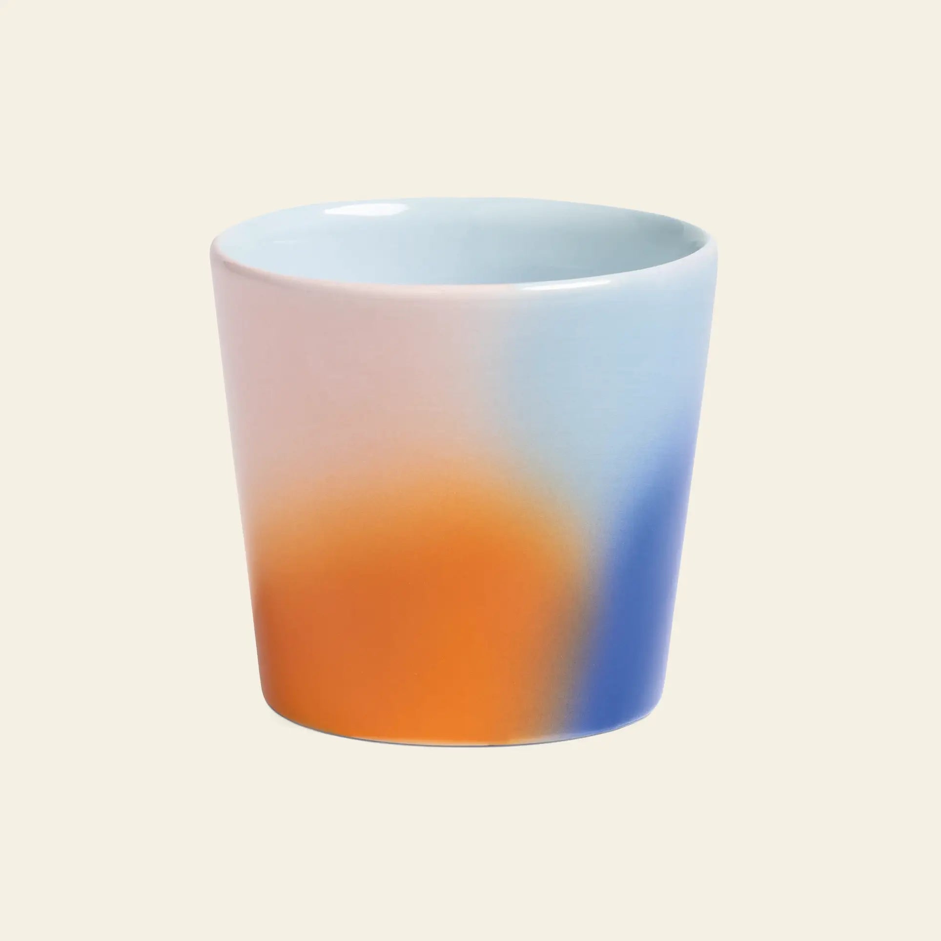 The &klevering Hue Mug Small, Set of 4 features smooth ceramic cups with gradient pastel designs in light blue, orange, and white, presented against a beige background.