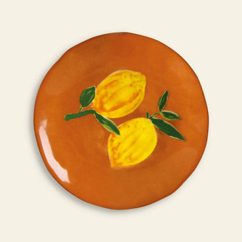 The &klevering Lemon Plate, Set of 4 by &klevering features round orange ceramic plates with a painted design of two yellow lemons and green leaves—ideal for adding a fresh, vibrant touch to your summer table.