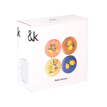 A white &klevering box displays four vibrant Lemon Plates, each with a unique lemon design on colorful pink, orange, yellow, and blue backgrounds. The front reads “Plate lemon.” Perfect for brightening your summer table.