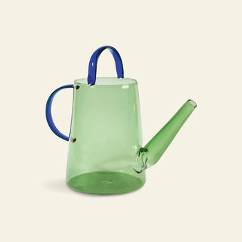 The &klevering Loop Watering Can by &klevering features a translucent green glass body, long spout, and blue top and side handles—ideal for watering your plants against a plain, light background.