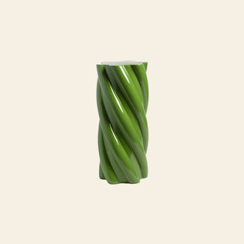 A glossy, green &klevering Marshmallow Pillar with a whimsical twisted cylindrical design stands centered on a plain light beige background.