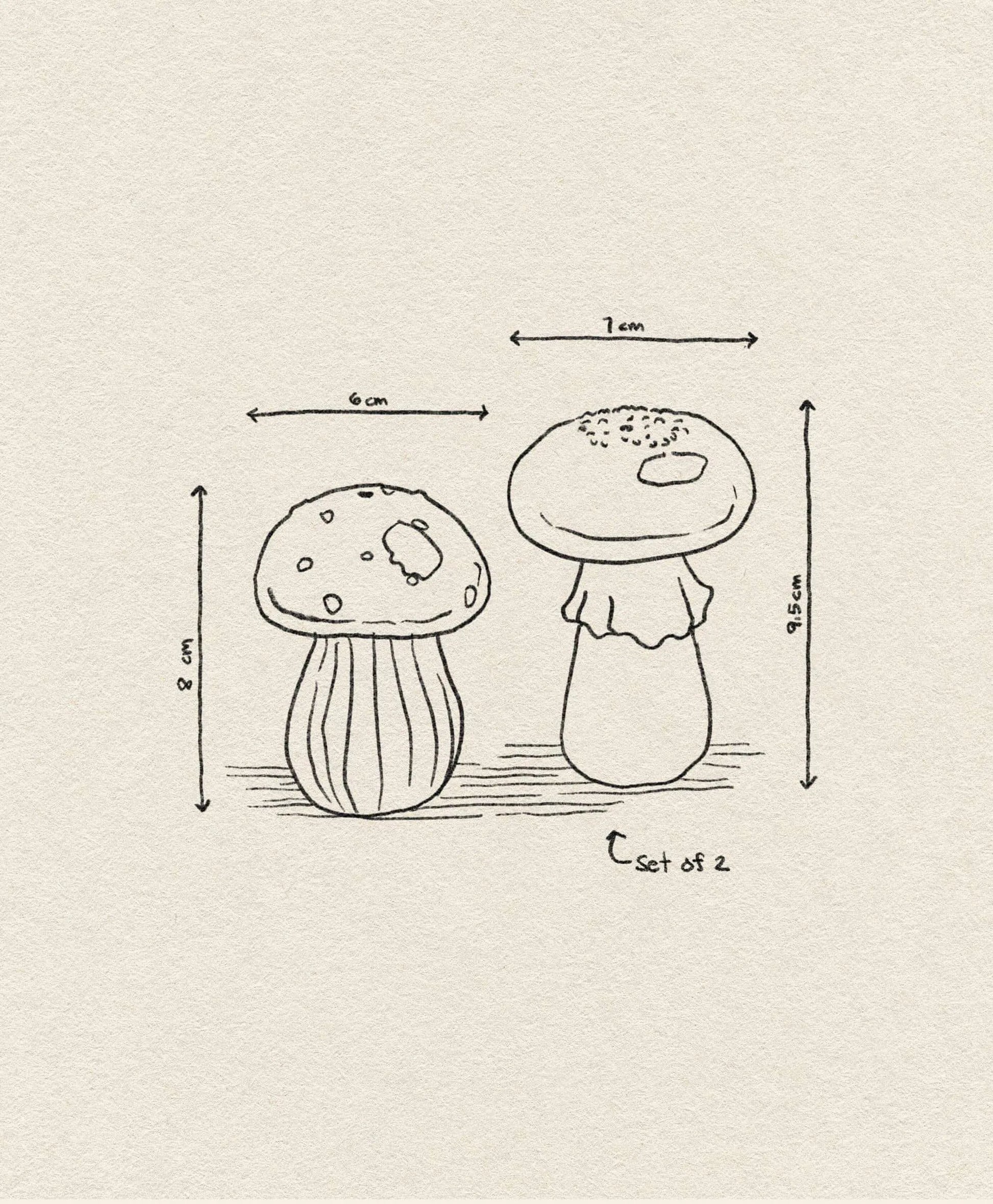 The &klevering Mushroom Salt & Pepper Set features a simple line drawing of two mushrooms (8x6 cm and 9.5x7 cm), labeled Set of 2 on a textured background—ideal as whimsical kitchen decor. Brand: &klevering.
