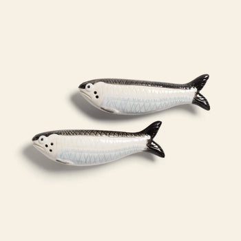 The &klevering Sardine Salt & Pepper Set by &klevering features two hand-painted ceramic fish in black, white, and light blue, inspired by marine beauty, presented against a plain beige background.