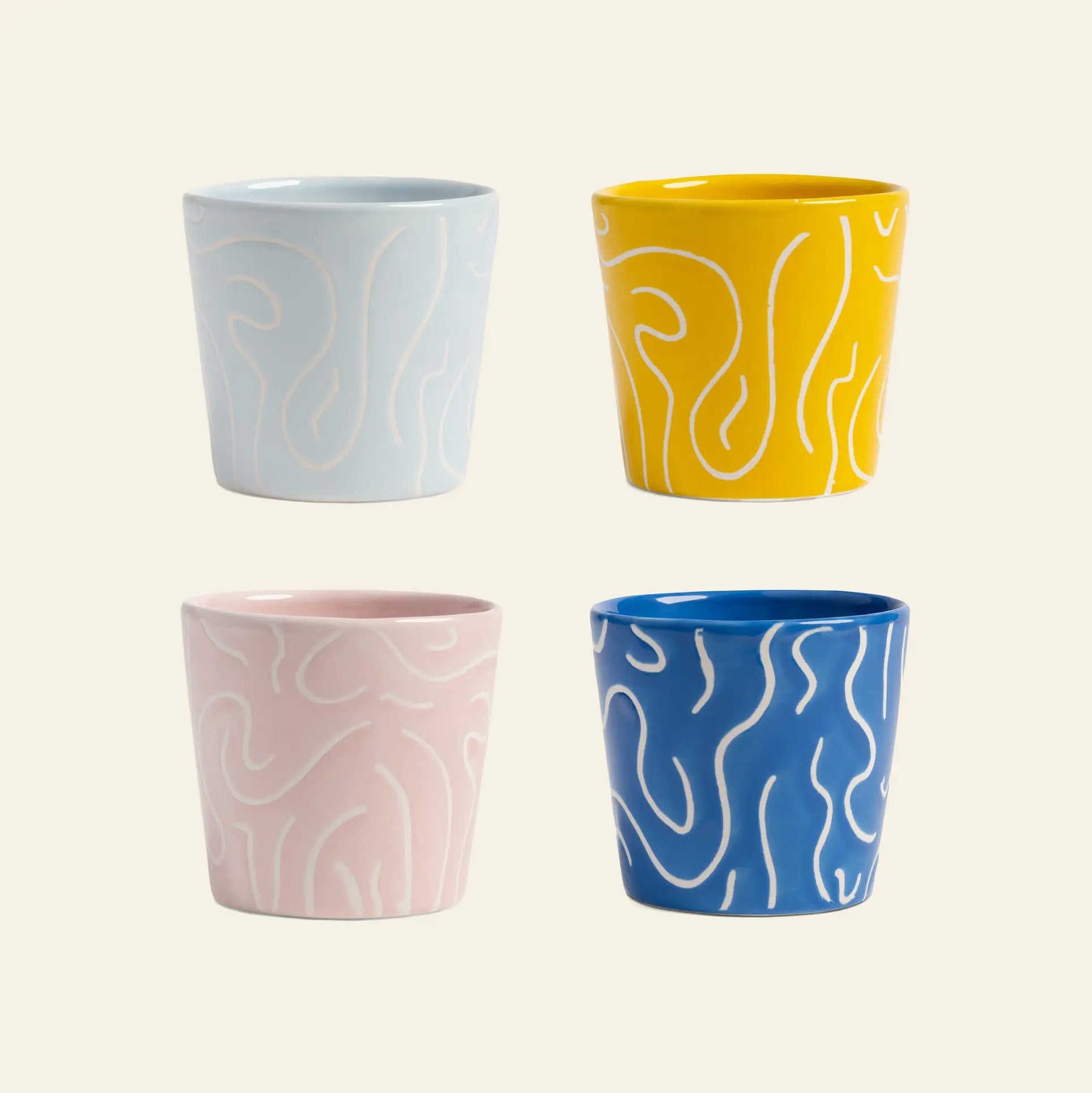 The &klevering Soba Mug Small Set of 4 features mugs in light blue, yellow, pale pink, and dark blue with white squiggly lines, shown in a two-by-two grid on a light background.