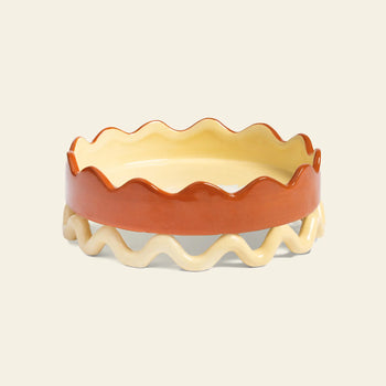 The &klevering Sway Tray is a ceramic pie dish with a wavy rim, beige interior, cream openwork base, and glossy reddish-brown exterior, adding both style and storage to your kitchen.