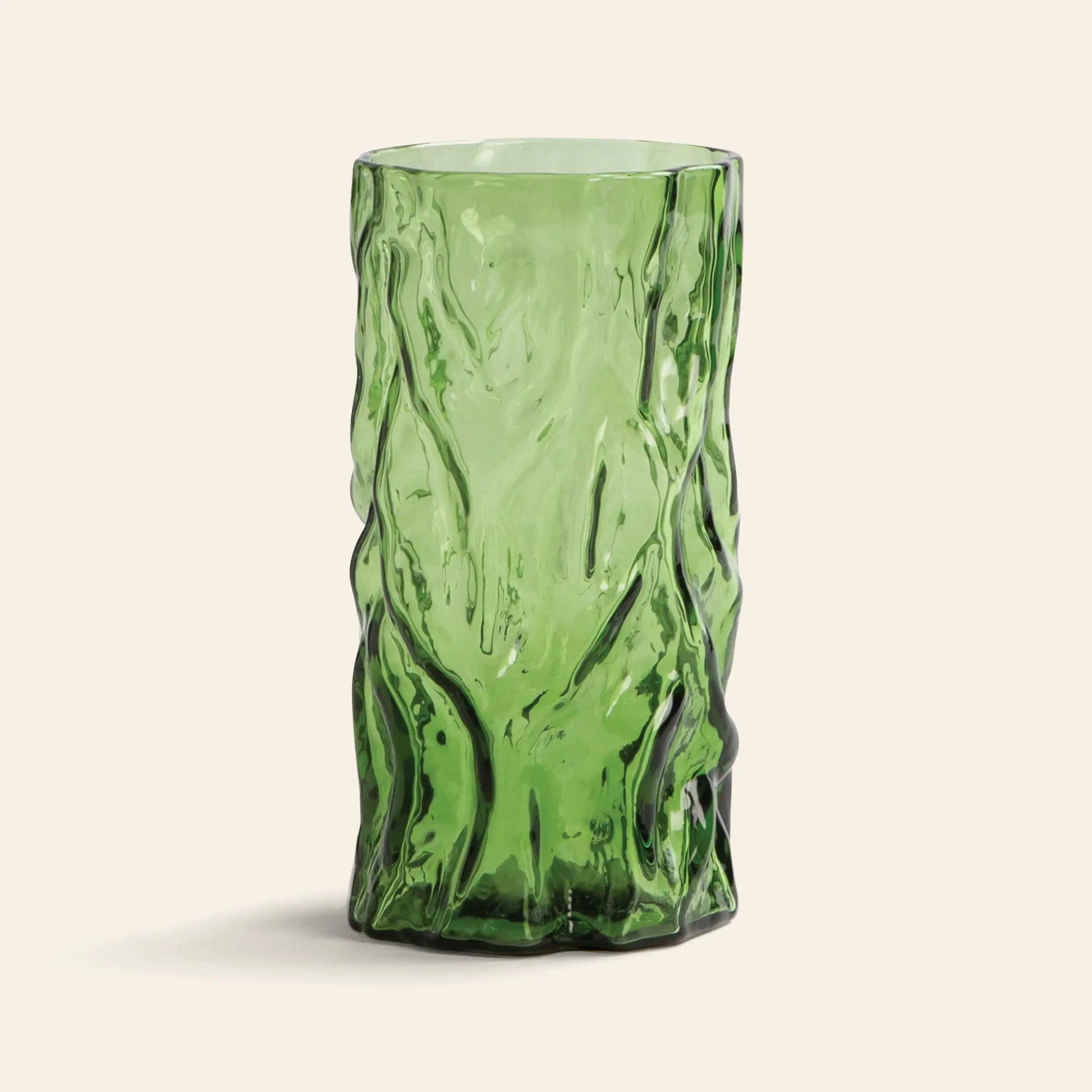 The &klevering Trunk Vase by &klevering is a tall green glass vase featuring a textured, organic crumpled design, reminiscent of decorative art, displayed against a simple light beige background.