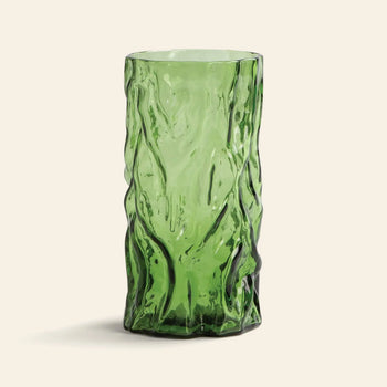 The &klevering Trunk Vase by &klevering is a tall green glass vase featuring a textured, organic crumpled design, reminiscent of decorative art, displayed against a simple light beige background.
