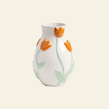 The &klevering Tulip Vase, Small, by &klevering, is a white ceramic piece featuring raised orange tulip motifs with green stems and leaves, inspired by the Netherlands and set against a light beige background.