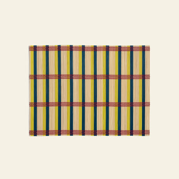 The &klevering Umami Placemat, Set of 4, features a rectangular bamboo design with green, yellow, and natural stripes plus red and purple bands—ideal for a vibrant dining setup. Displayed on a plain beige background.