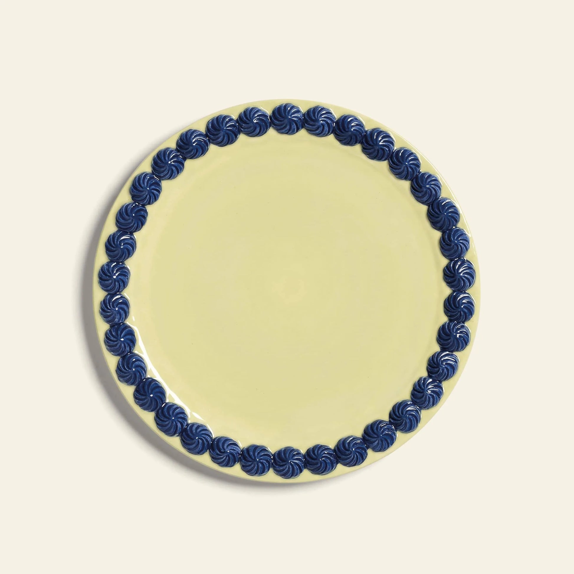 The &klevering Whipped Plate, Set of 4 features round pale yellow plates with a dark blue swirling border on a light beige background.