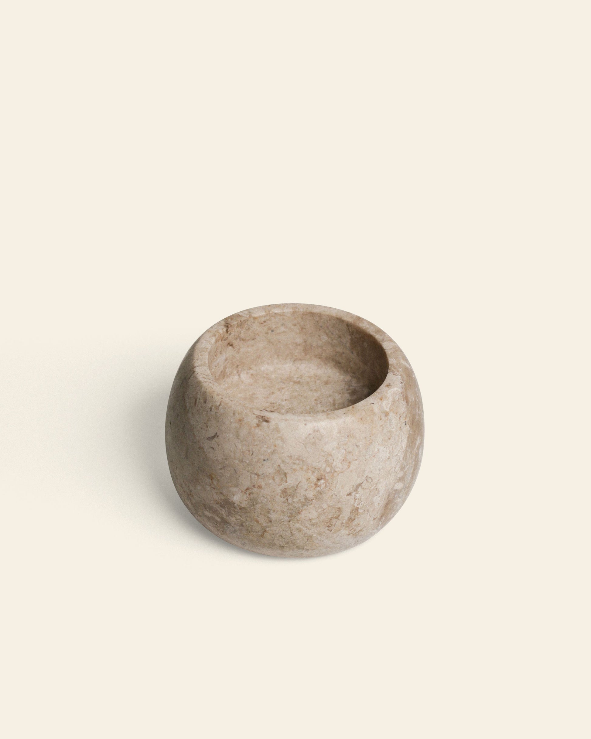 The stillgoods Abel Duo Holder, a round, shallow marble piece in light beige with a smooth finish, serves as a minimalist tealight candle holder and is showcased on an off-white background.
