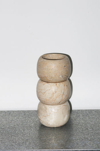 Three round, beige stone stillgoods Abel Duo Holders are stacked atop each other against a plain white background, positioned on a gray speckled surface.
