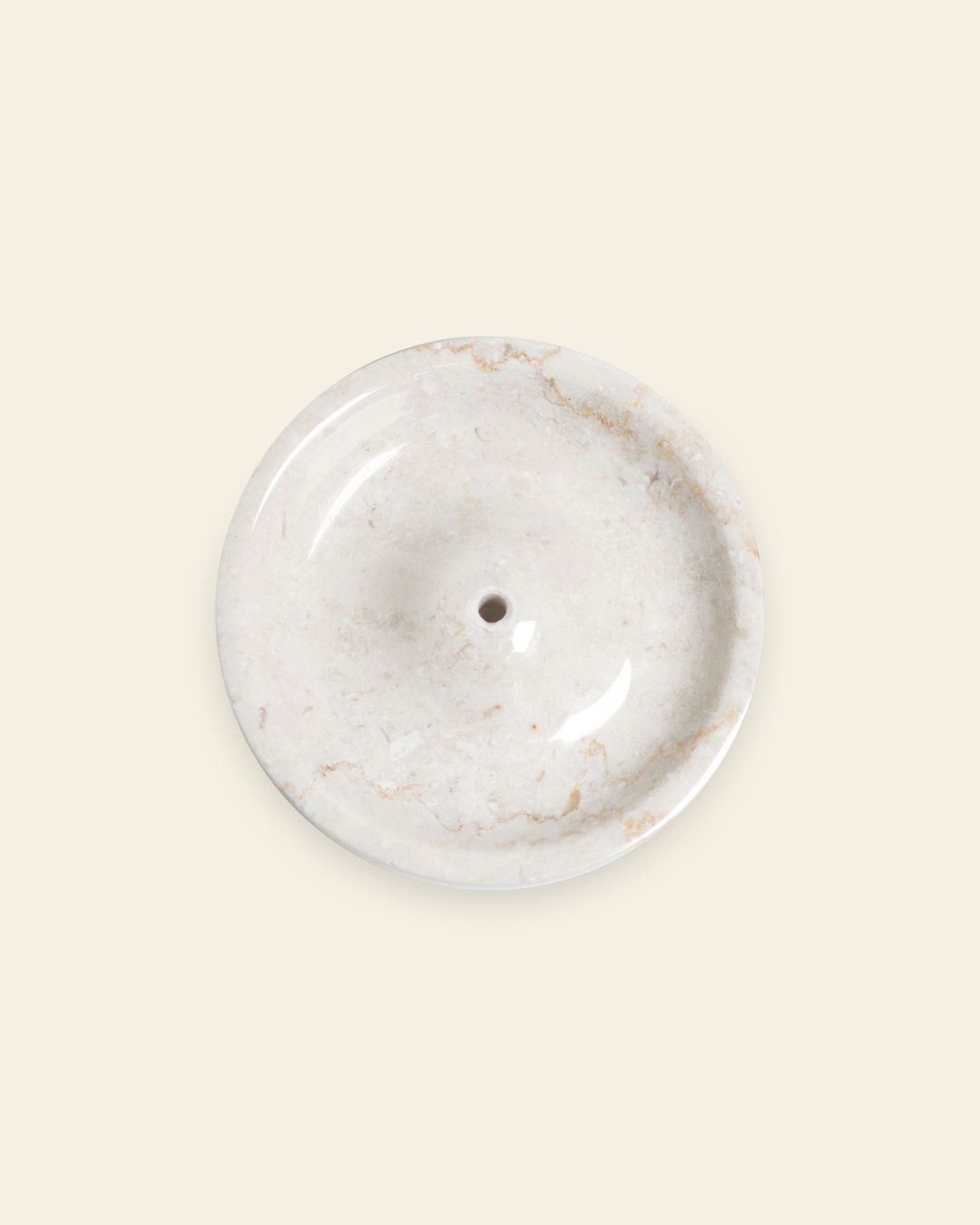 The stillgoods Ebb Incense Holder is a round, white marble dish with a subtle marbled pattern and central drainage hole. Shown on a light beige background, it’s perfect as an accessory tray or minimalist incense holder for your space.