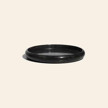 The stillgoods Harmony Tray is a black, round, low-profile tray with a smooth, glossy finish—ideal for displaying decor or serving as a marble centerpiece. Shown here against a plain cream background.
