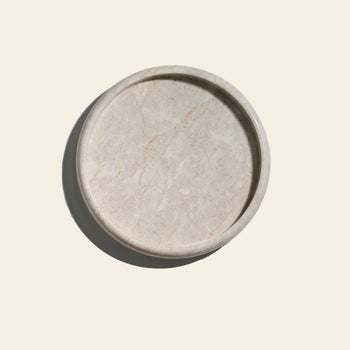 The stillgoods Harmony Tray by stillgoods is a round, light beige marble centerpiece with subtle veining—ideal for elevating your home decor and displaying elegant decorative objects.