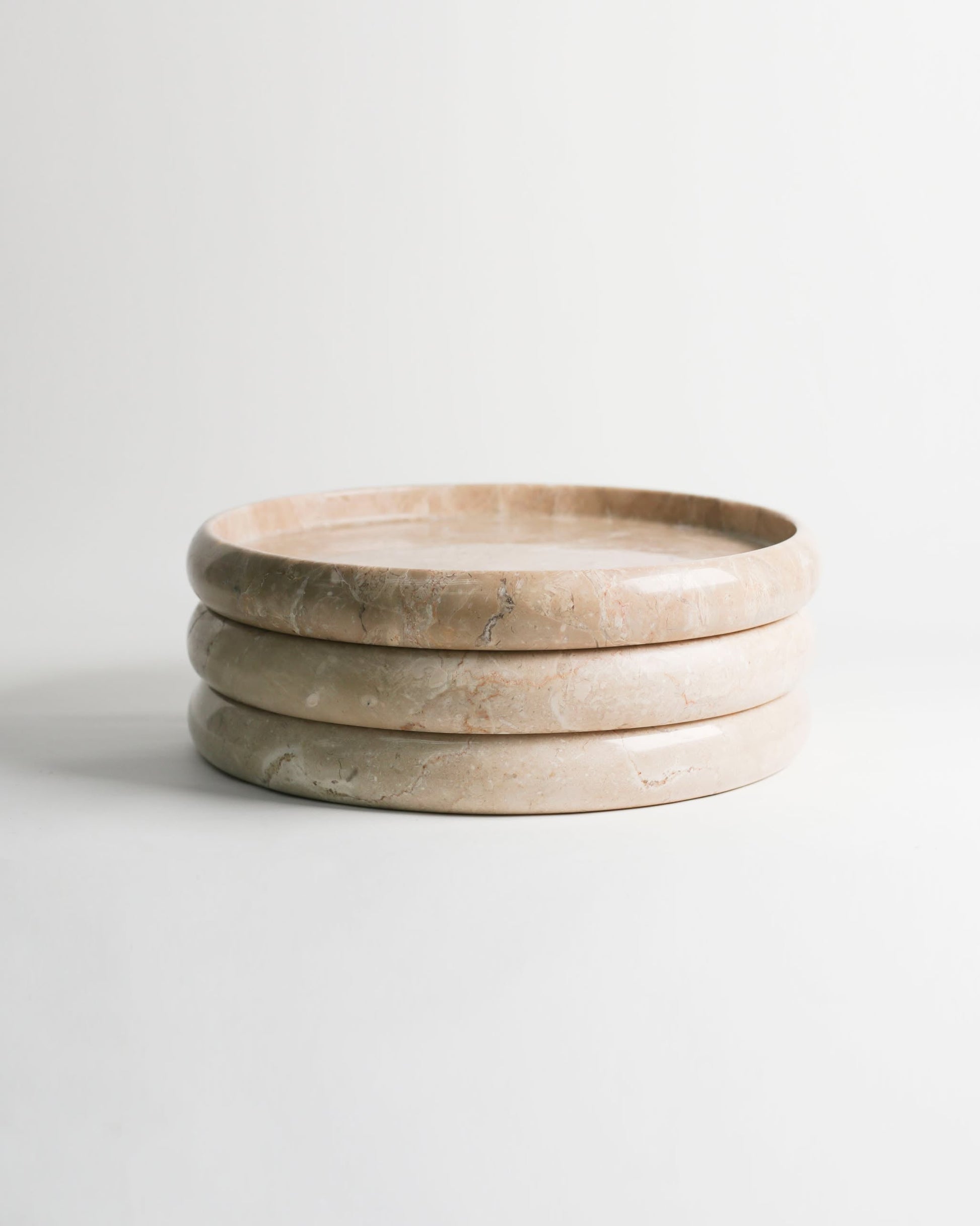 The stillgoods Harmony Tray by stillgoods features three stacked, round beige marble layers, adding sophisticated elegance to any home decor when displayed against a plain white background.