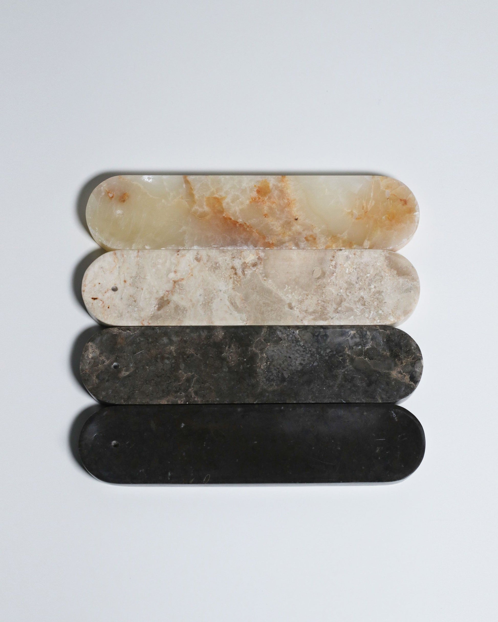The stillgoods Horizon Incense Holder by stillgoods features four oval stones stacked vertically, with colors fading from light cream to dark black—an elegant and versatile accent for any modern space.