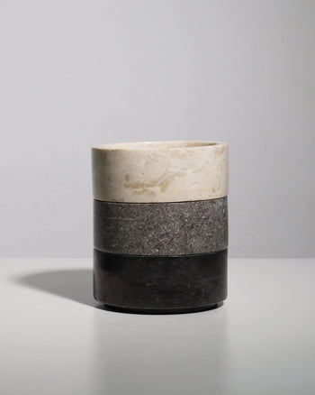 The stillgoods Tingkat Bowl, a cylindrical bowl with three stacked sections in light beige, gray, and dark brown marble, is displayed on a white surface against a plain light gray background.